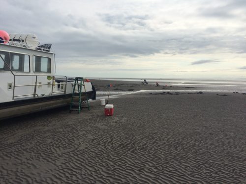 One of our boats on dry ground with a cooler next to it and people in the distance