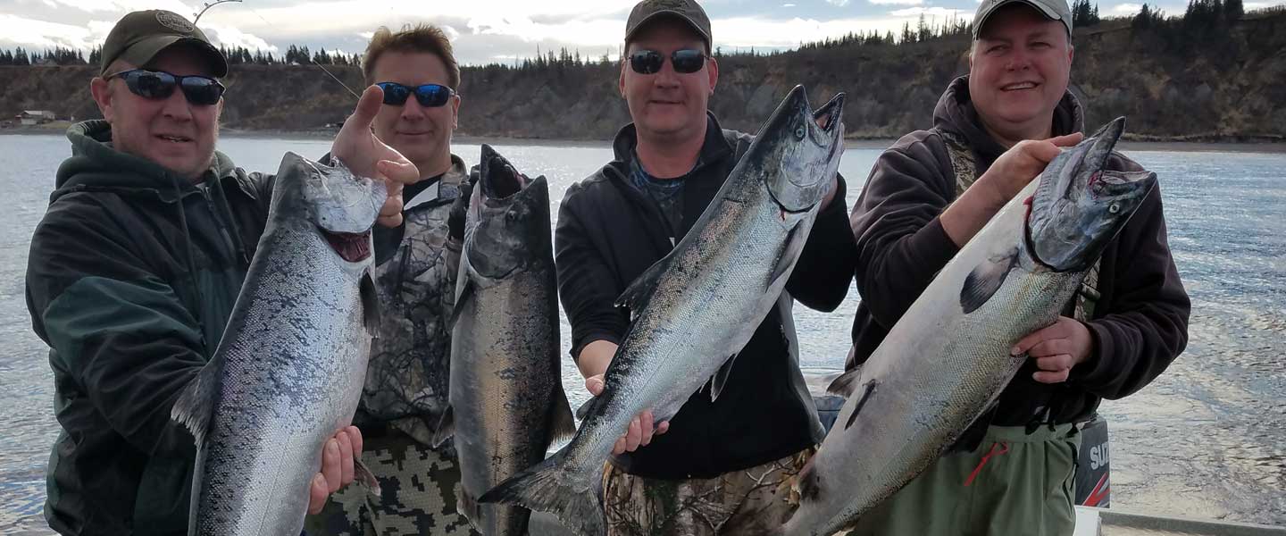 Four guys holding up big salmon