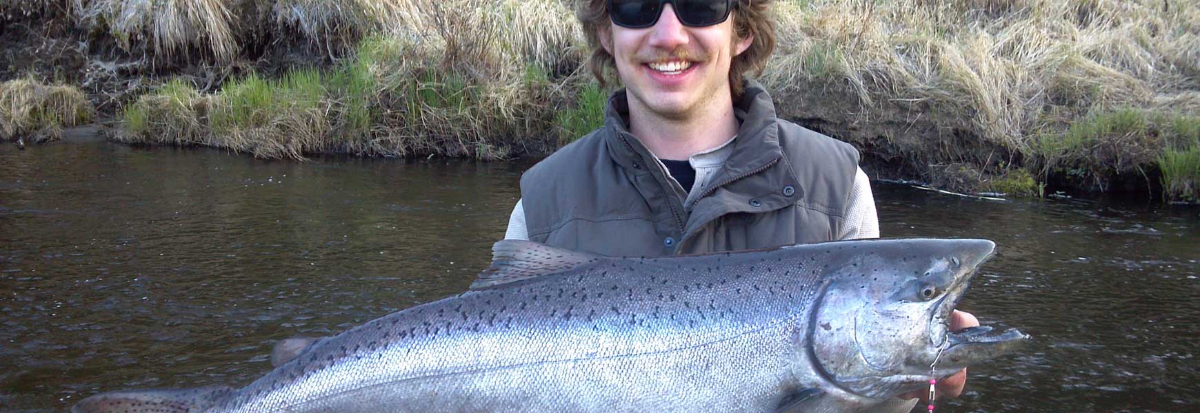 Man holding salmon by river